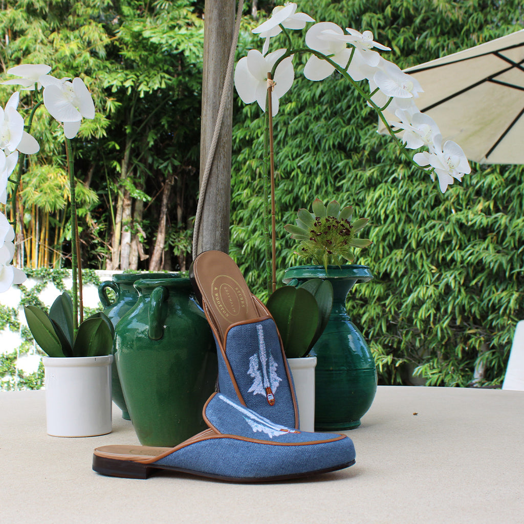 A pair of blue slippers resting on a table with plants and trees in the background