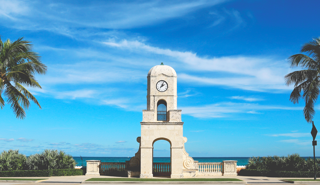 A photograph of the Palm Beach clocktower photographed here with the ocean in the background.