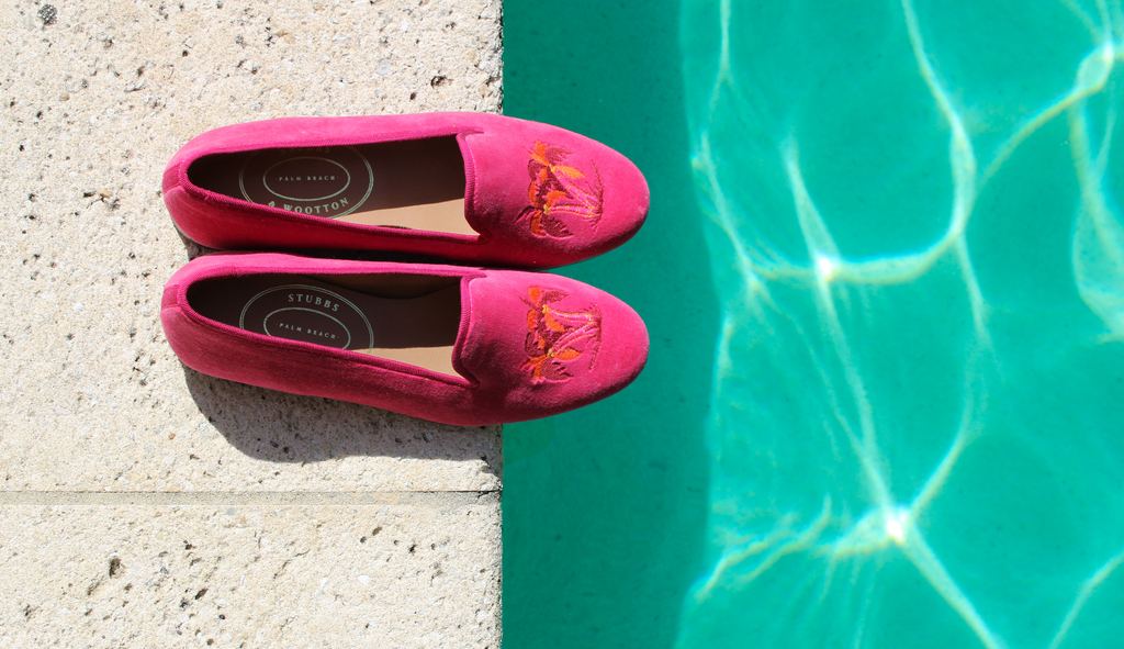 A pair of pink slippers photographed here on the edge of a pool deck.