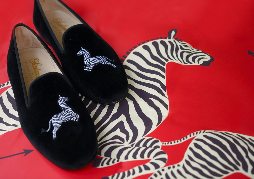 black slippers with zebra embroidery on zebra wallpaper
