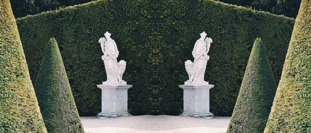 A reflected image of a statue in a garden.