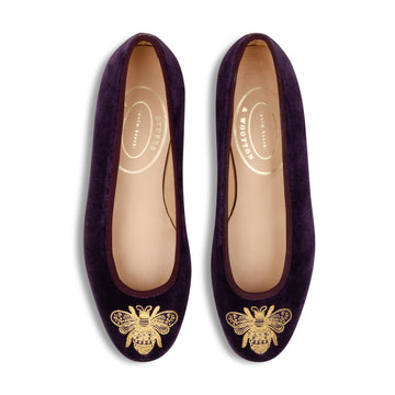 Pair of purple shoes with gold bee designs on a white background