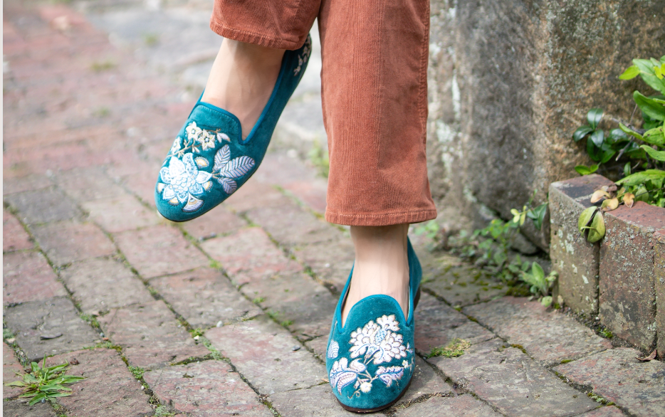 A woman's feet wearing blue embroidered slippers
