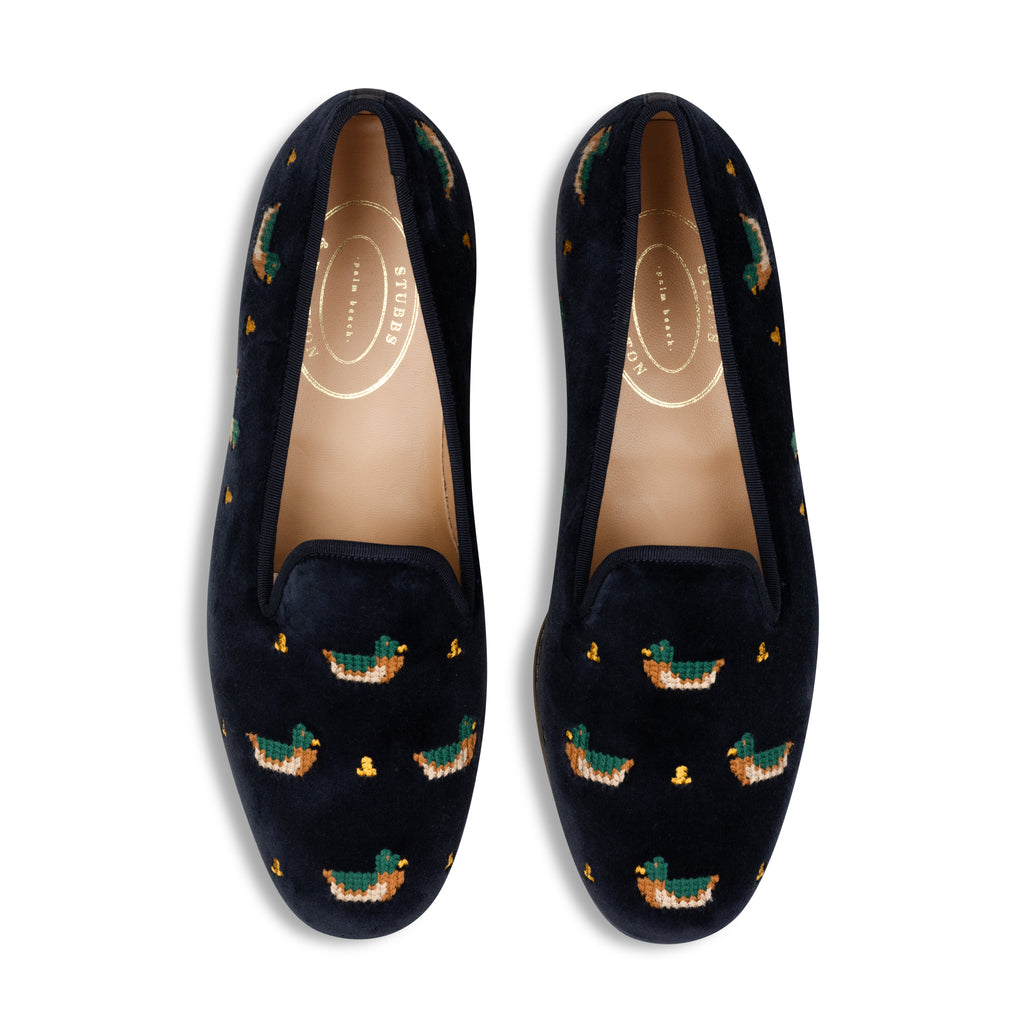 Navy velvet slippers with embroidered duck patterns on a white background