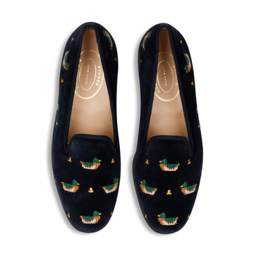 Navy velvet slippers with embroidered duck patterns on a white background