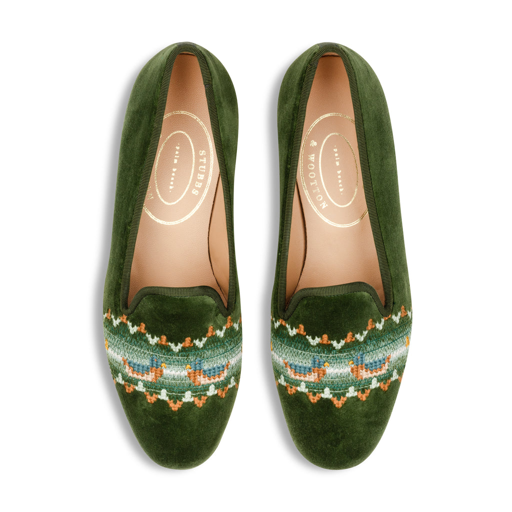 Green velvet slippers with intricate pattern on a white background