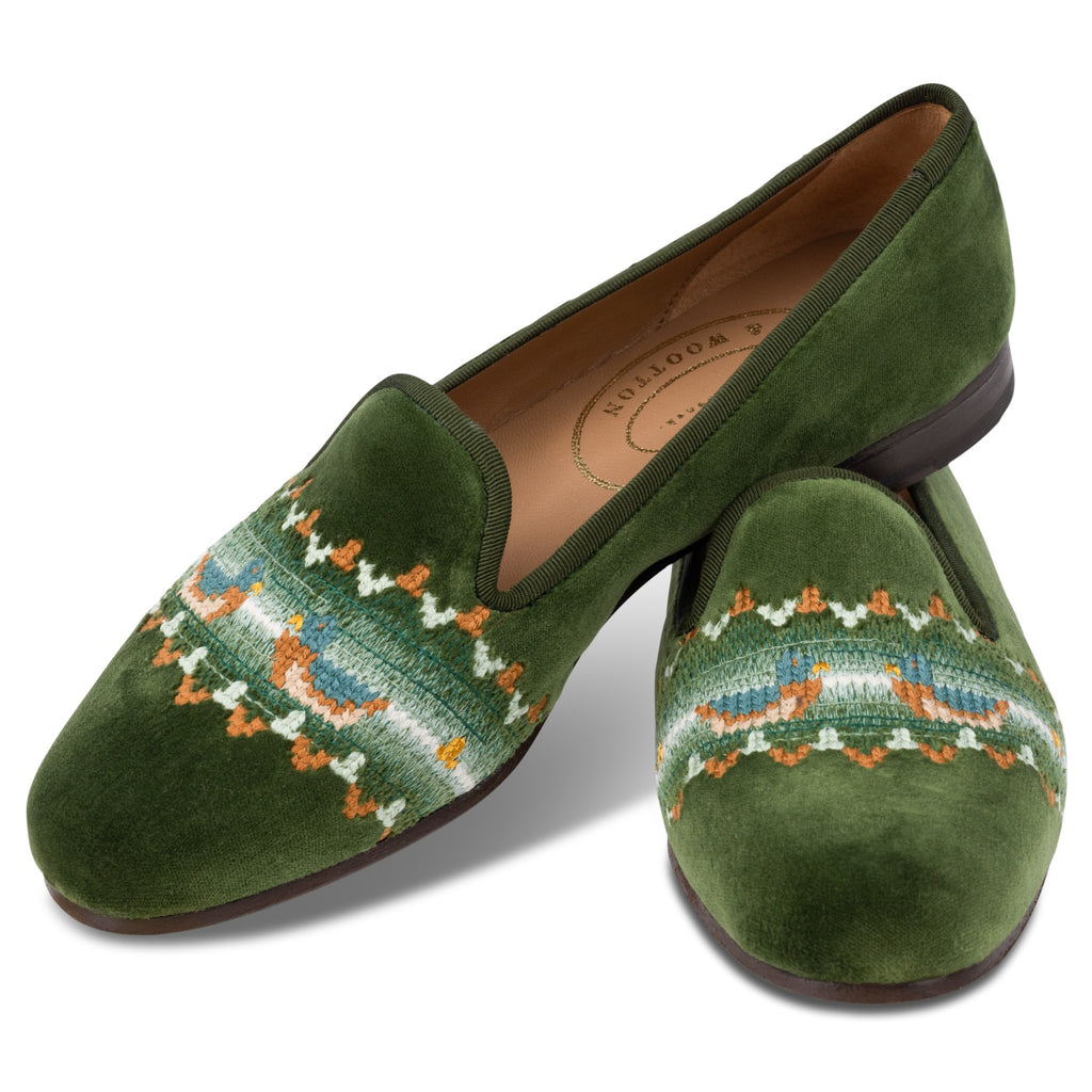 Green velvet slippers with intricate pattern on a white background